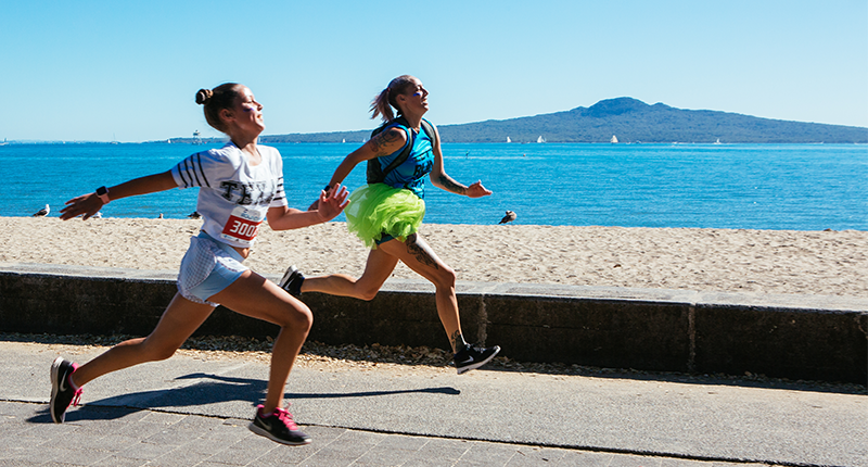 Two women running on Auckland's waterfront with Rangitoto in the background