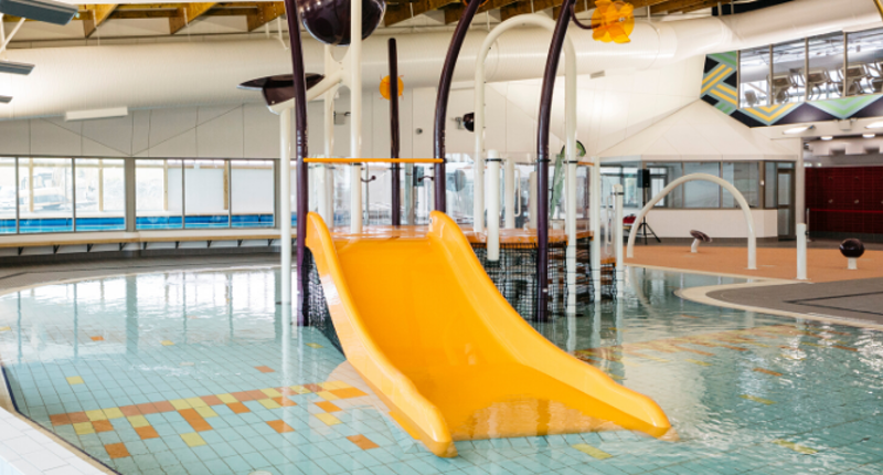 Bright yellow plastic water slide feature at the Albany Stadium Pools