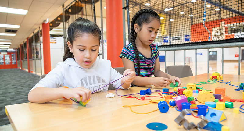 two children sitting at a table playing with toys