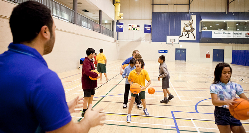group of children doing basketball drills with instructor in the foreground