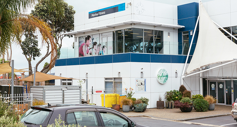 A white building with navy blue accents and a marina fitness signage
