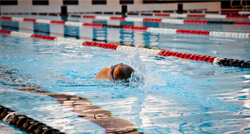 young boy taking a breath while swimming a length