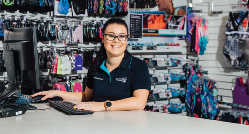 female standing behind a reception desk and smiling