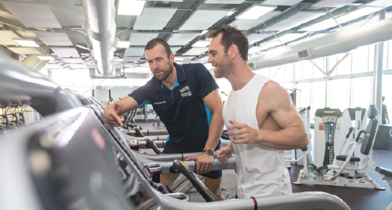 male fitness instructor showing a male how to use a treadmill