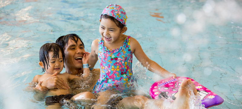 father with his son and daughter playing in the pool