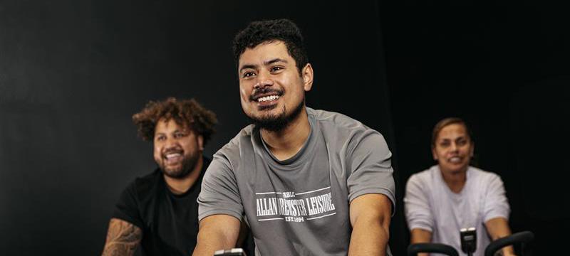 three people smiling riding stationary bikes in gym