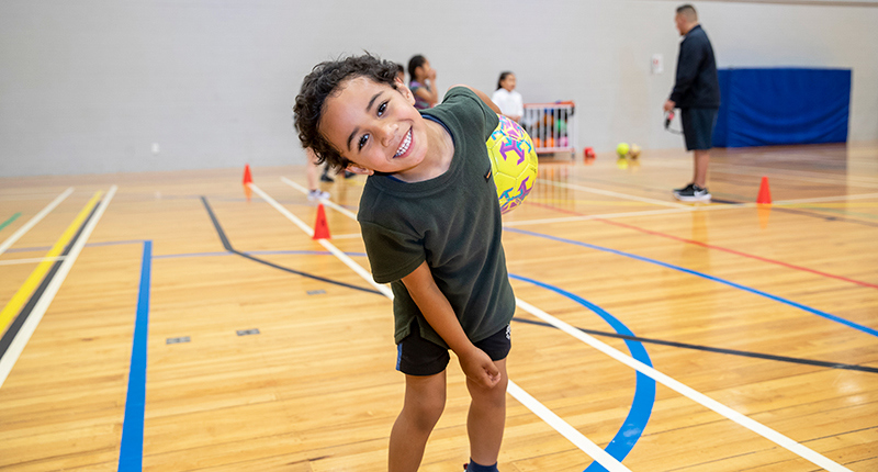 young boy with checky grin with ball